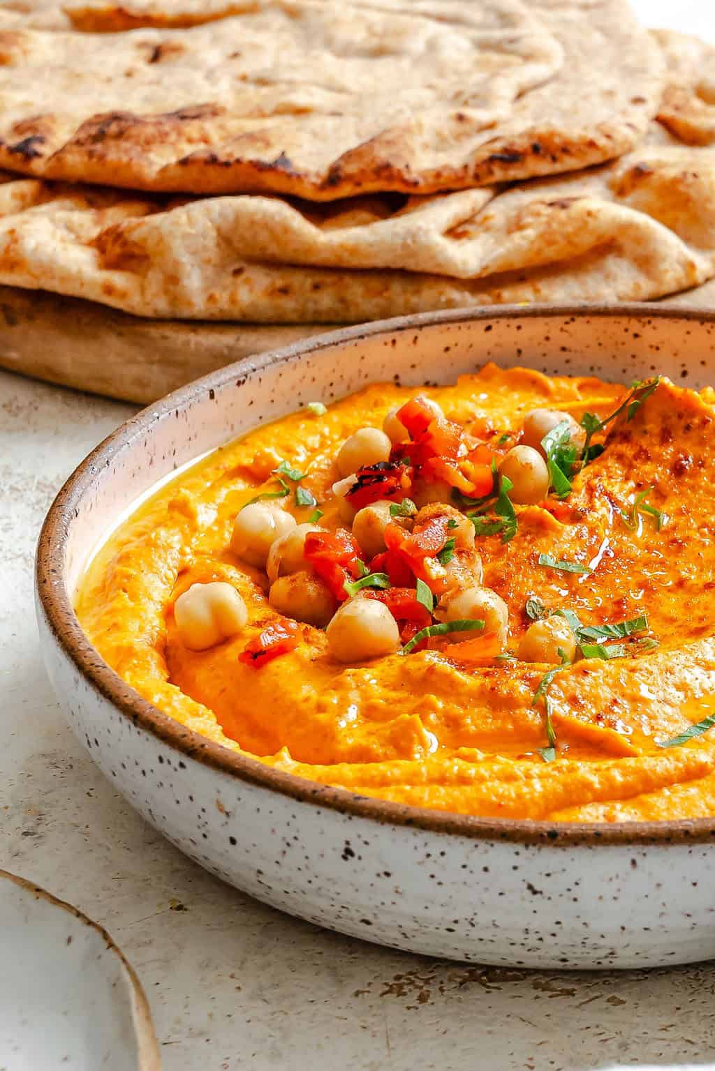 Roasted Red Pepper Hummus in a white bowl with pita