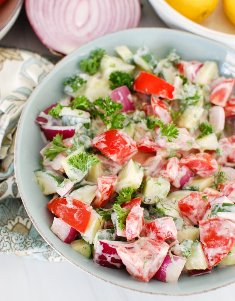 Tomato Cucumber Salad with Yogurt Dressing in teal bowl
