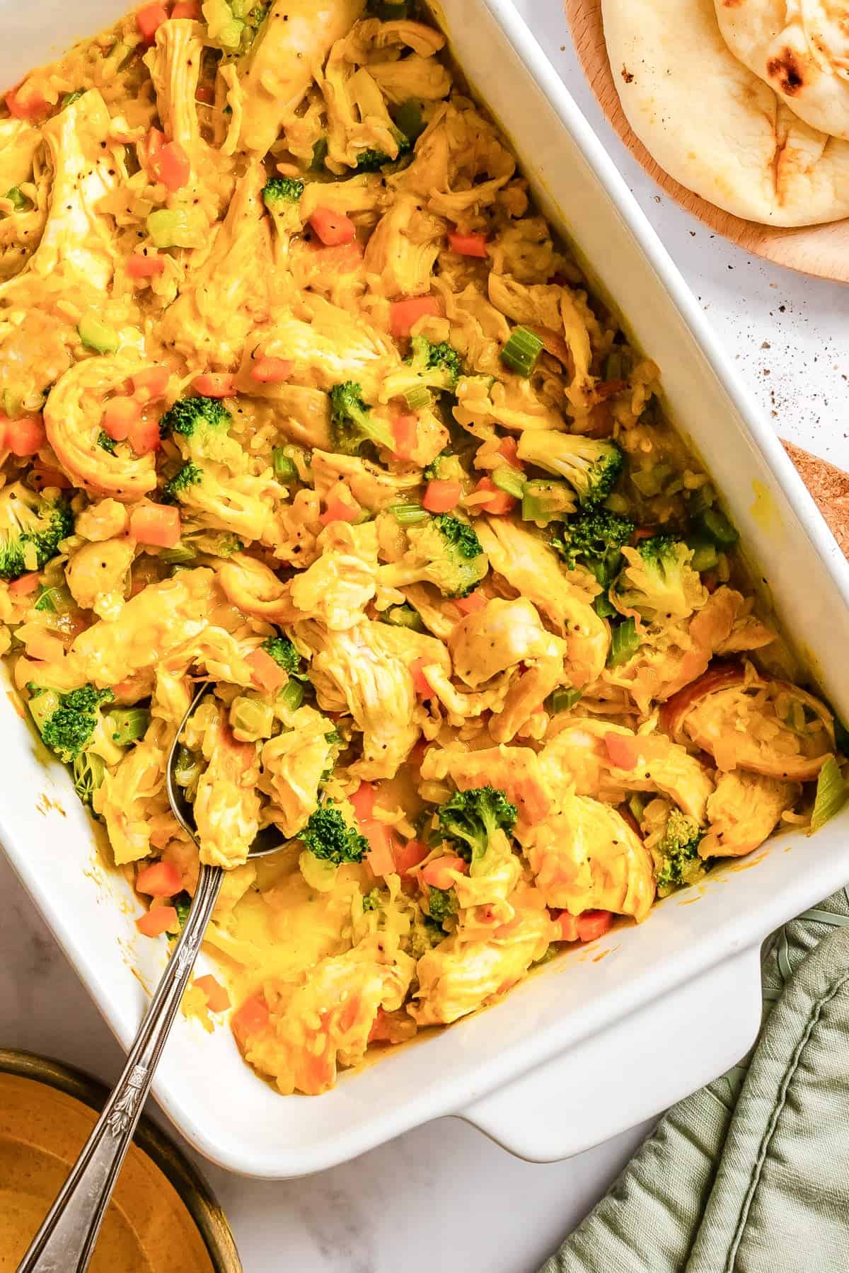 Serving curried chicken and rice casserole from a baking dish with a large spoon