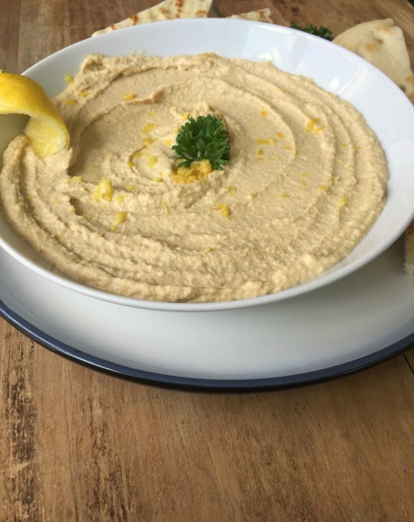 Lemon Hummus in bowl on wood board 