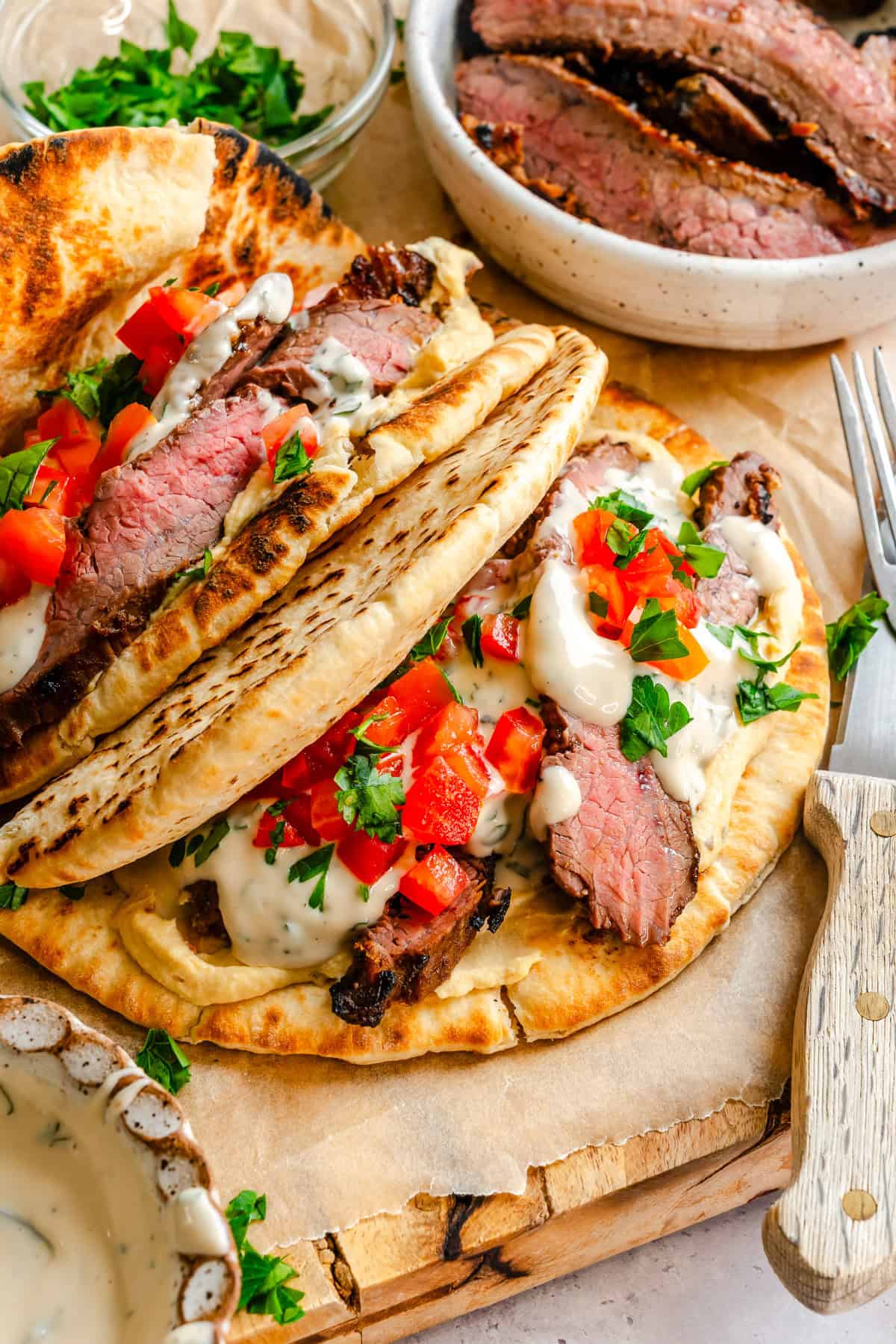 Quick Mediterranean Steak Pita Wrap on a cutting board with yogurt sauce