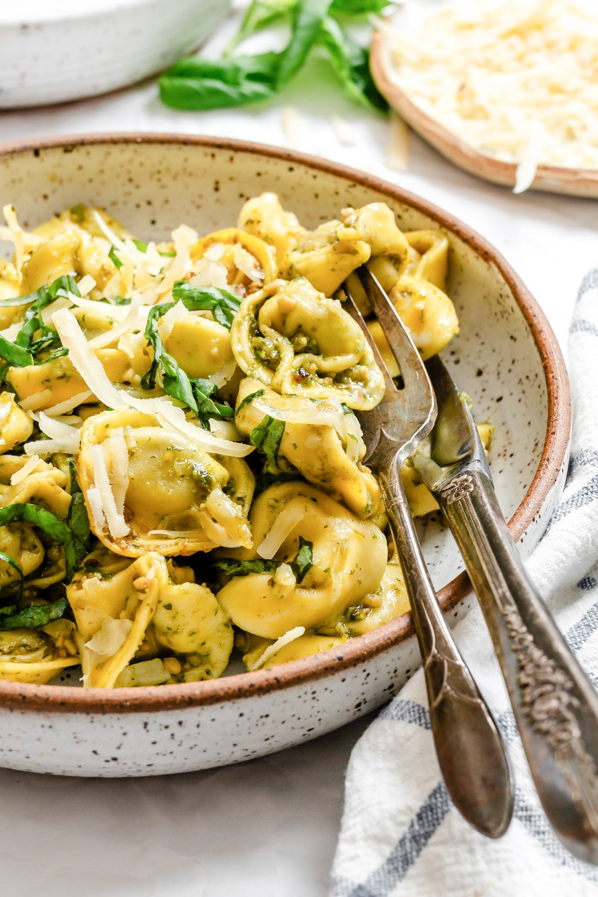 tortellini in a bowl with a fork and knife resting on the side