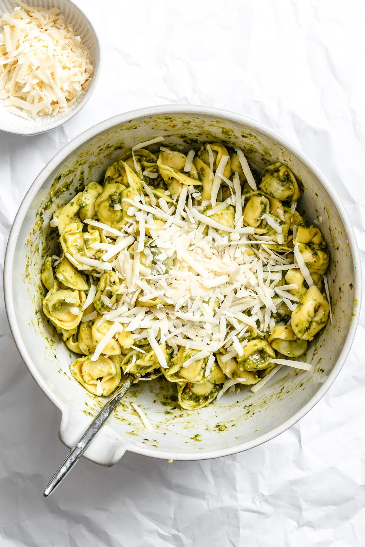 tortellini in a large bowl mixed with pesto and cheese
