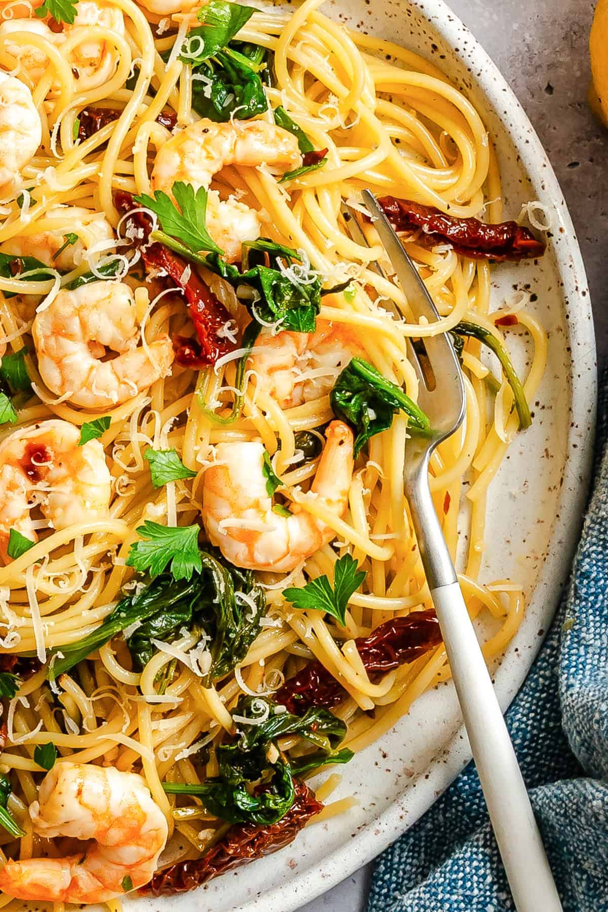 Easy shrimp scampi pasta with sun-dried tomatoes and spinach on a white plate