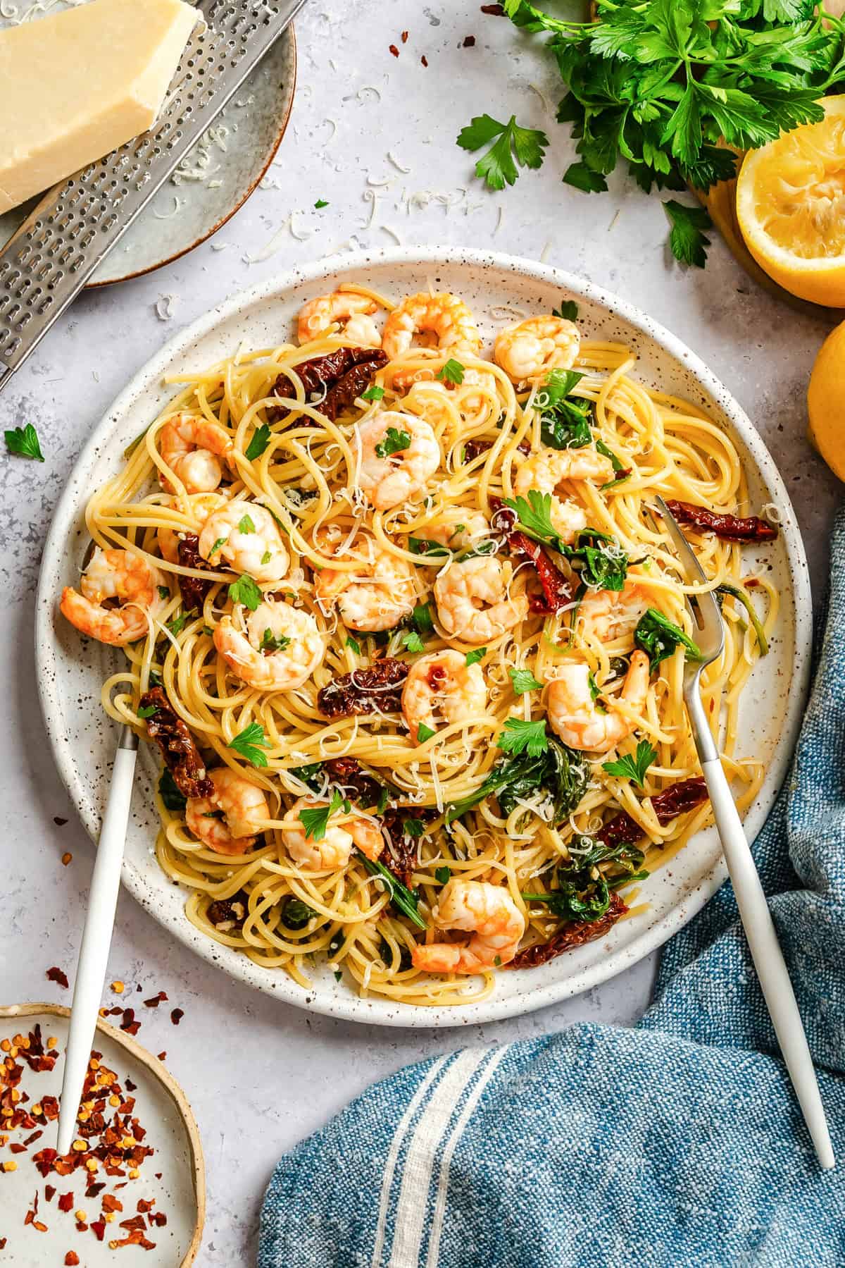 Shrimp scampi with fettuccine, spinach, and sun-dried tomatoes garnished with parmesan and lemon zest