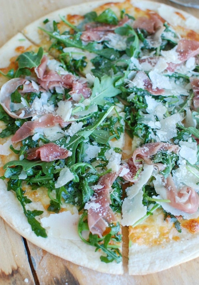 Prosciutto Arugula Pizza on a cutting board. 