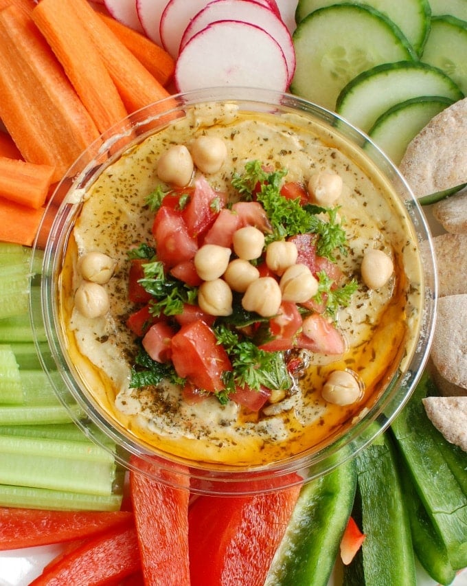 Creamy hummus is topped with diced tomatoes, fresh parsley and mint, chickpeas, pine nuts and a squeeze of lemon juice. Serve this with a rainbow of vegetables and whole wheat pita.