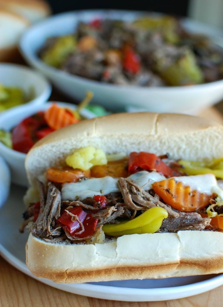 Slow Cooker Italian Beef Sandwiches make a great game day food or weeknight dinner that easily cooks in your crockpot. Chuck roast is slowly cooked in Italian seasonings, beef broth and mixed with pepperoncini peppers and Giardiniera. Toast the beef in a hoagie bun with provolone cheese and extra pepperoncini and Giardiniera for the perfect sandwich.