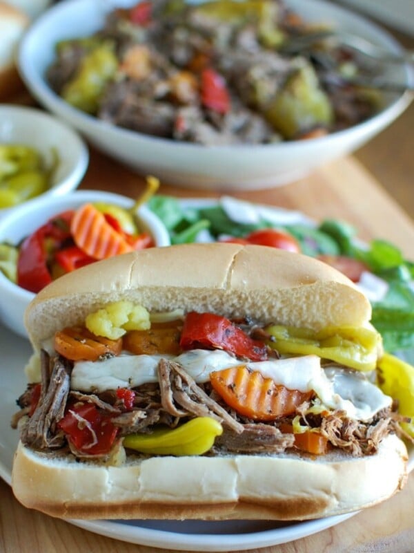 Slow Cooker Italian Beef Sandwiches make a great game day food or weeknight dinner that easily cooks in your crockpot. Chuck roast is slowly cooked in Italian seasonings, beef broth and mixed with pepperoncini peppers and Giardiniera. Toast the beef in a hoagie bun with provolone cheese and extra pepperoncini and Giardiniera for the perfect sandwich.