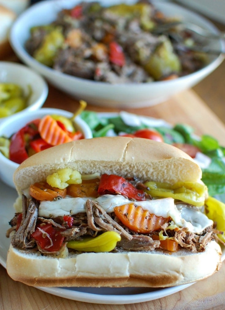 Slow Cooker Italian Beef Sandwiches make a great game day food or weeknight dinner that easily cooks in your crockpot. Chuck roast is slowly cooked in Italian seasonings, beef broth and mixed with pepperoncini peppers and Giardiniera. Toast the beef in a hoagie bun with provolone cheese and extra pepperoncini and Giardiniera for the perfect sandwich.