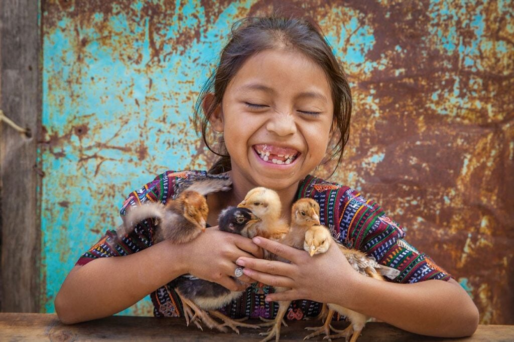 Yennifer holds baby chicks her family received as a part of the Gift Catalog program.