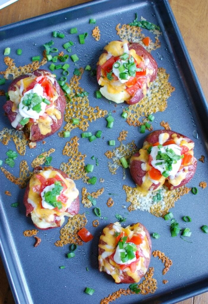 Loaded Smashed Potatoes are crispy on the outside and soft on the inside and loaded with cheese, sour cream, tomatoes, green onion and cilantro. These make an easy family meal or appetizer for game day or a party!