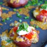 Loaded Smashed Potatoes are crispy on the outside and soft on the inside and loaded with cheese, sour cream, tomatoes, green onion and cilantro. These make an easy family meal or appetizer for game day or a party!