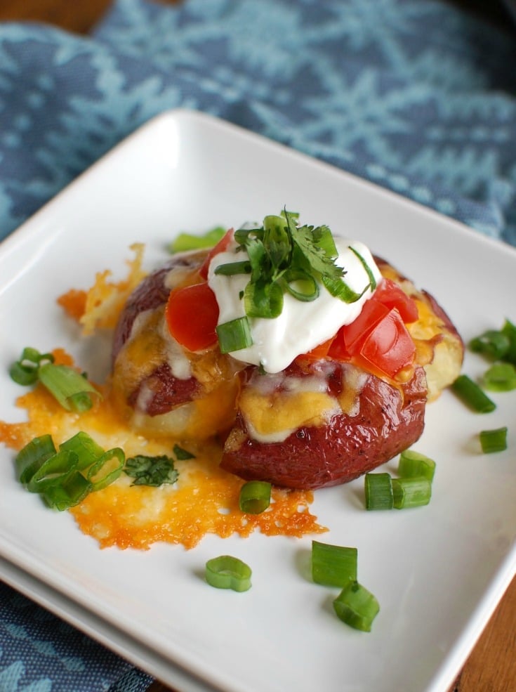 Loaded Smashed Potatoes are crispy on the outside and soft on the inside and loaded with cheese, sour cream, tomatoes, green onion and cilantro. These make an easy family meal or appetizer for game day or a party! 