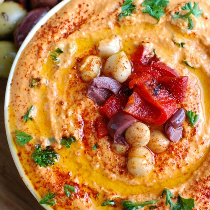 Roasted Red Pepper Greek Yogurt Hummus is a creamy dip that pairs nicely with pita bread or fresh vegetables. Chickpeas, tahini, lemon juice, spices and fire roasted red peppers are blended with Greek yogurt for added protein and creaminess making this not only healthy, but delicious!