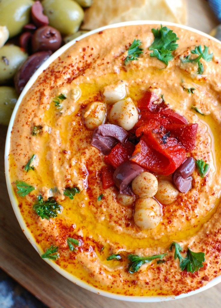 Roasted Red Pepper Greek Yogurt Hummus is a creamy dip that pairs nicely with pita bread or fresh vegetables. Chickpeas, tahini, lemon juice, spices and fire roasted red peppers are blended with Greek yogurt for added protein and creaminess making this not only healthy, but delicious! 