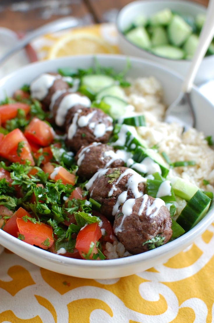 A bowl of salad topped with Mediterranean-style meatballs.