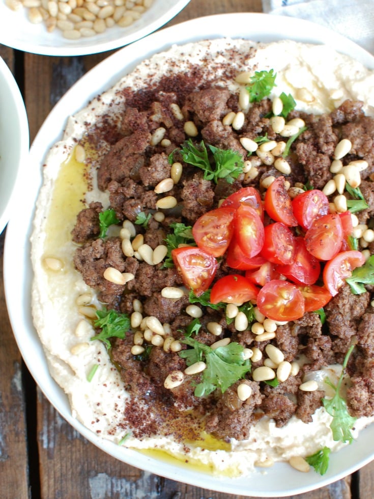 Hummus with Spiced Beef and Toasted Pine Nuts is an easy appetizer, lunch or dinner featuring creamy hummus topped with warm, spiced beef, toasted pine nuts, freshly chopped tomatoes and parsley. It is gluten-free and full of protein. 