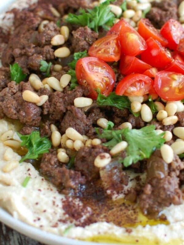 Hummus with Spiced Beef and Toasted Pine Nuts on white plate