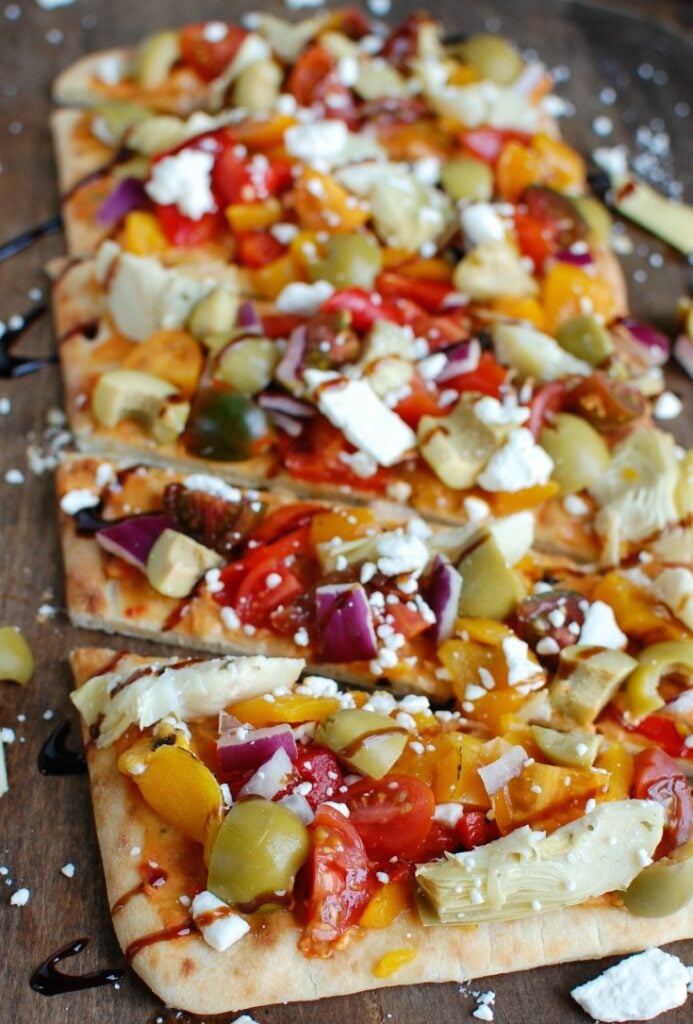 Mediterranean Flatbread is a quick and easy vegetarian meal made on your favorite flatbread or naan. Your favorite Mediterranean flavors of hummus, olives, artichokes, roasted peppers, feta cheese, tomatoes, red onion and balsamic glaze create a colorful, flavor packed appetizer or meal. 