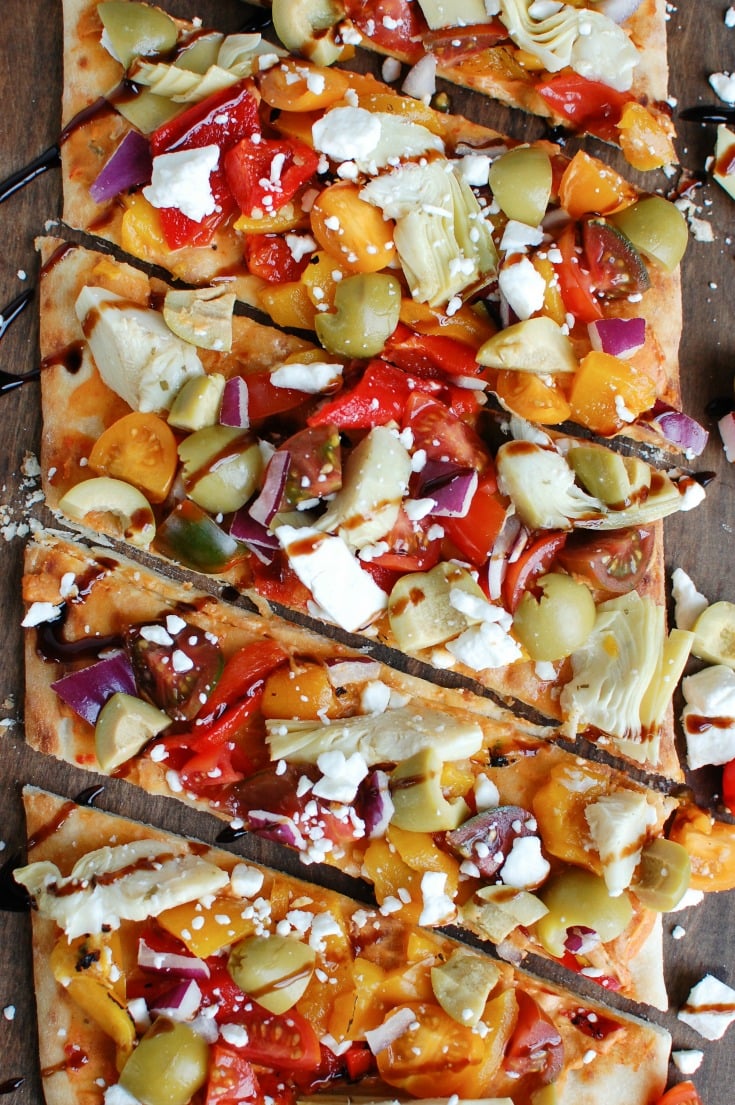 Mediterranean Flatbread is a quick and easy vegetarian meal made on your favorite flatbread or naan. Your favorite Mediterranean flavors of hummus, olives, artichokes, roasted peppers, feta cheese, tomatoes, red onion and balsamic glaze create a colorful, flavor packed appetizer or meal. 