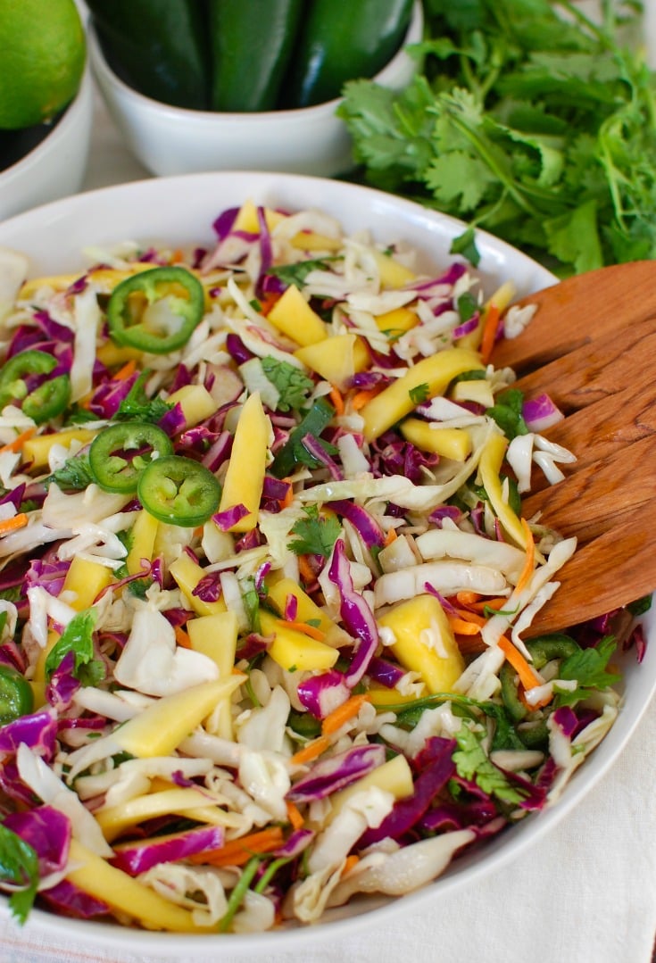 Easy Mango Cabbage Coleslaw with wooden spoons. 
