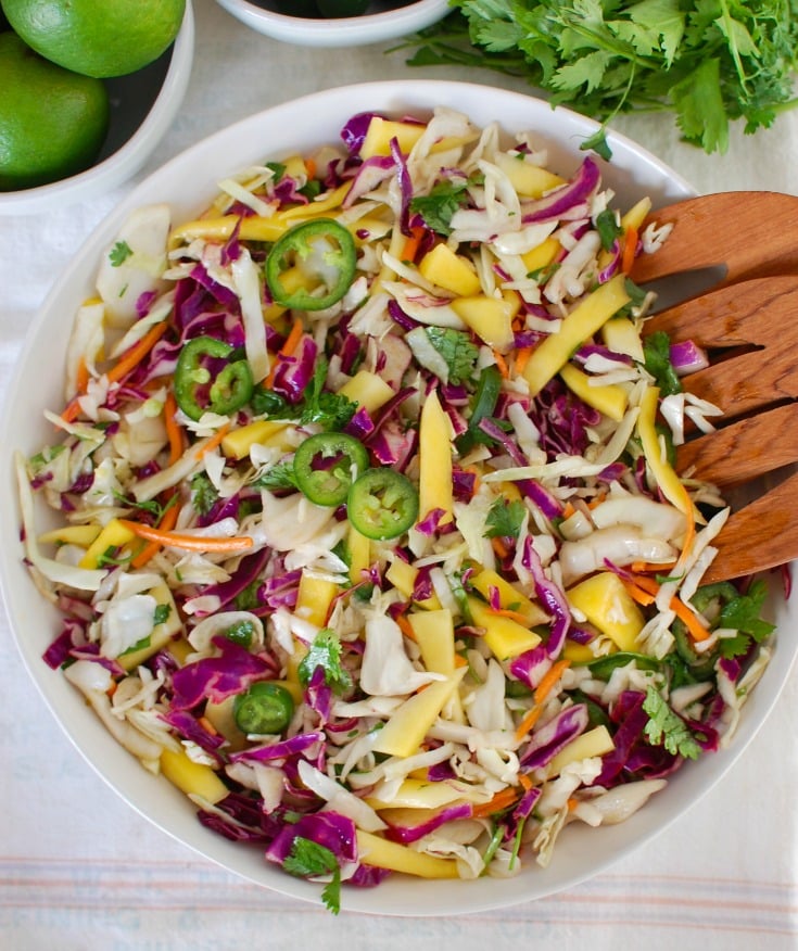Easy Mango Cabbage Coleslaw with wooden serving spoons. 