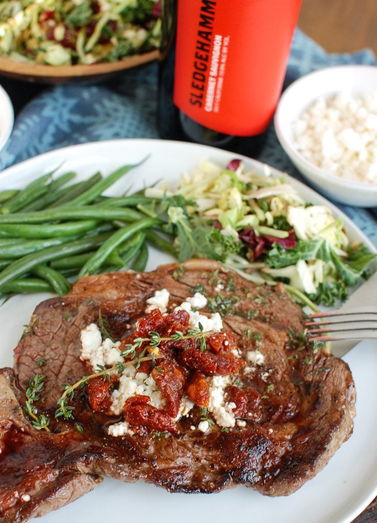 Pan-Seared Ribeye with Goat Cheese and Sun-dried Tomatoes on a White Plate 