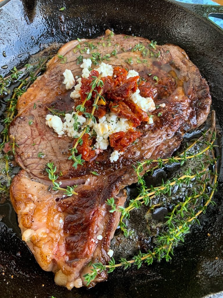 Pan-Seared Ribeye with Goat Cheese and Sun-dried Tomatoes in Skillet