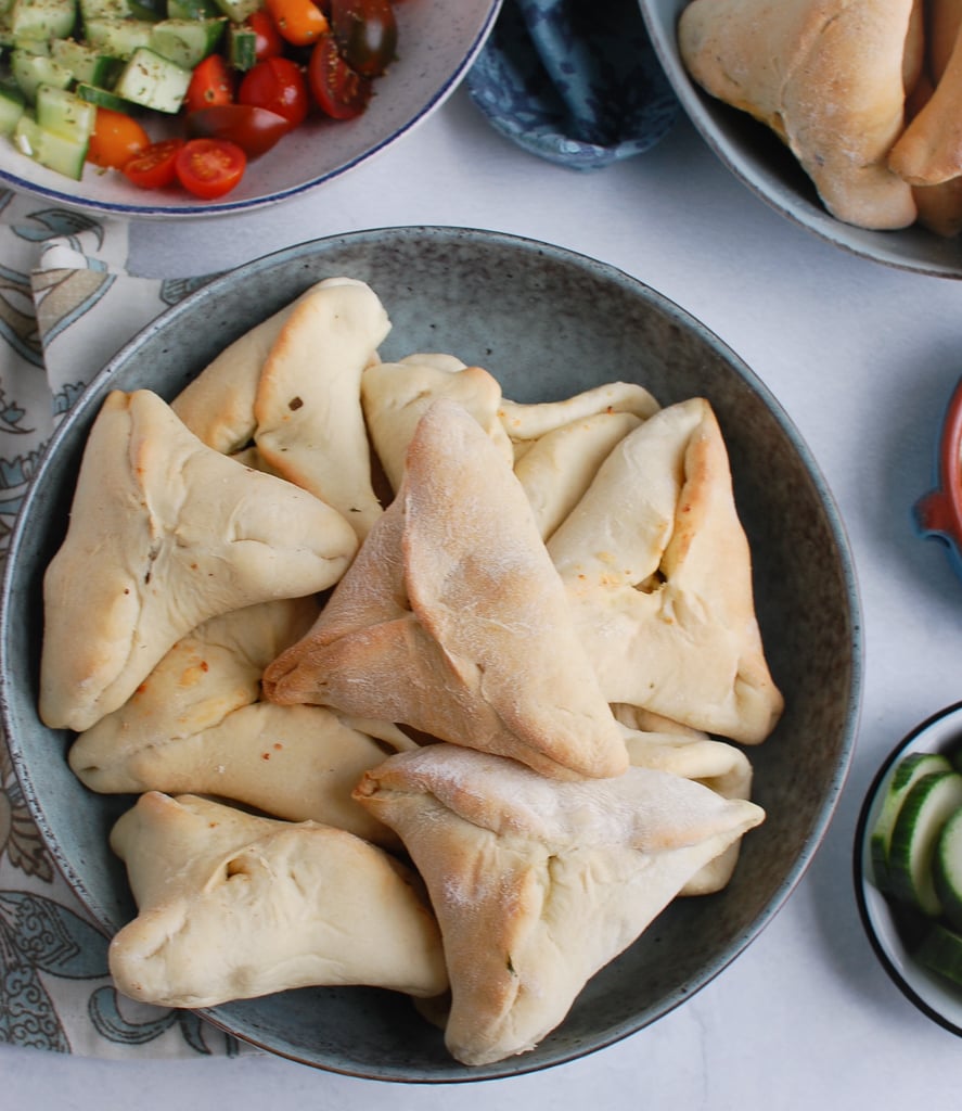 triangles of spinach stuffed in dough in a small bowl.