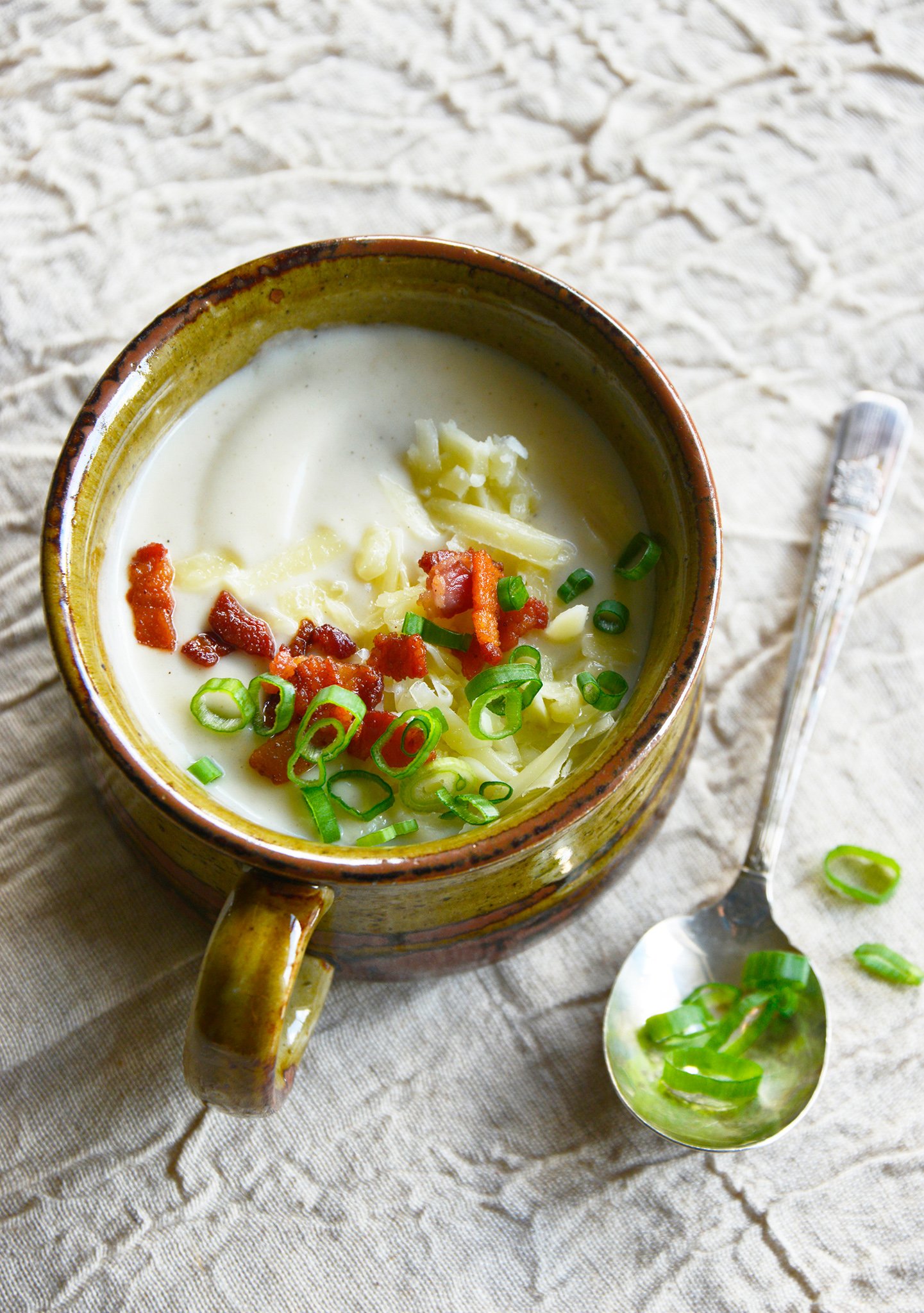 Instant Pot Cauliflower Soup with spoon and green onions on top.