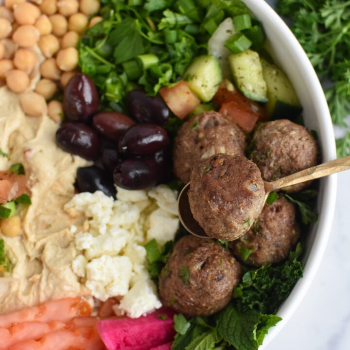 Lamb Kofta in a hummus bowl with a fork.