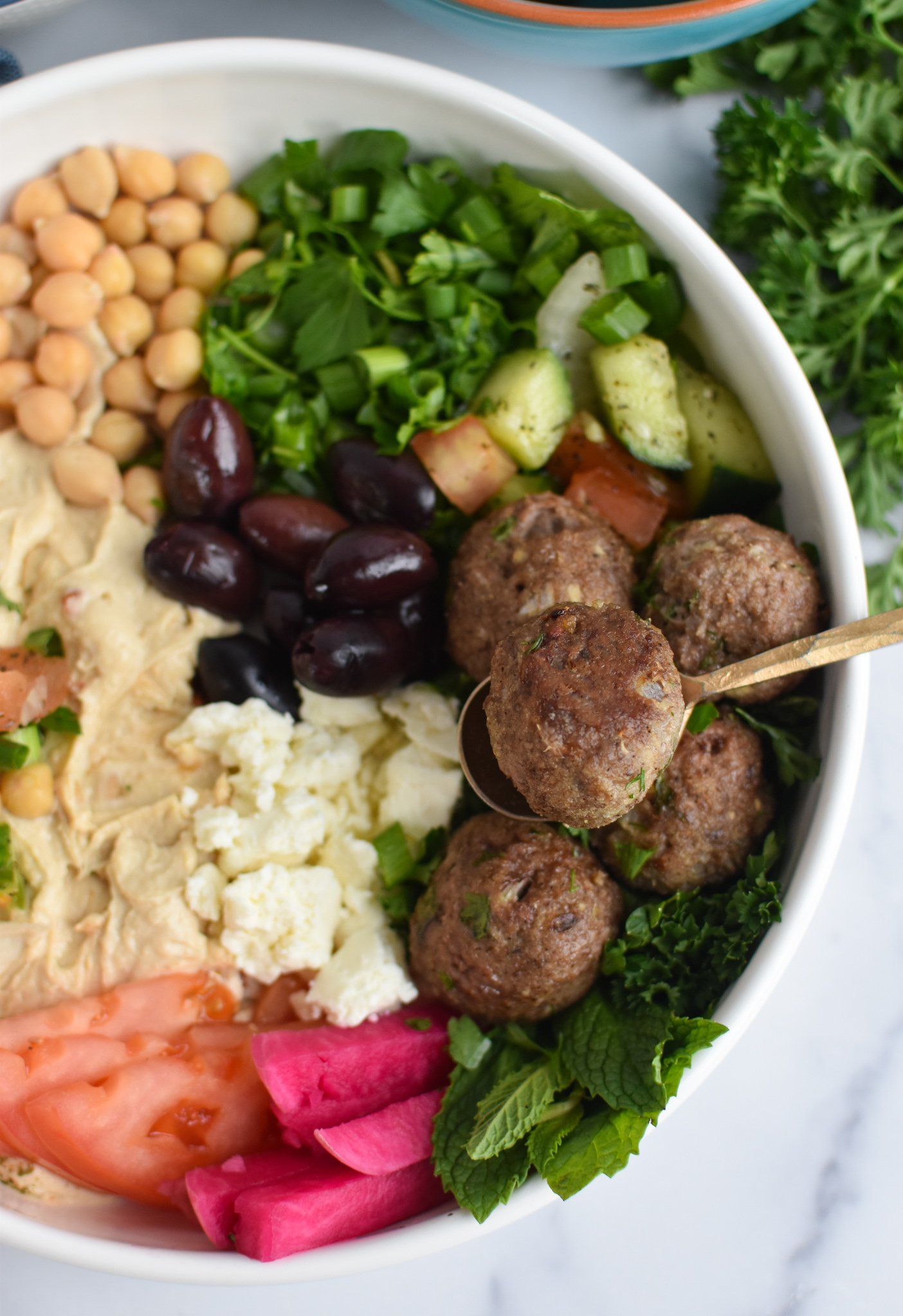 Lamb Kofta in a hummus bowl with a fork.