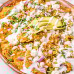 Chilaquiles Rojos Recipe on a platter with avocado on top.