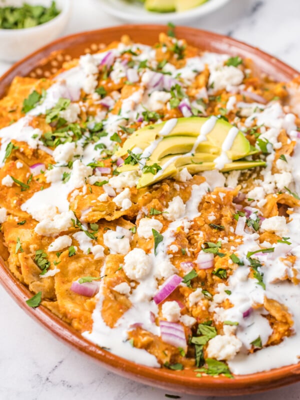 Chilaquiles Rojos Recipe on a platter with avocado on top.