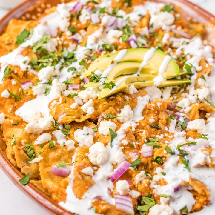 Chilaquiles Rojos Recipe on a platter with avocado on top.