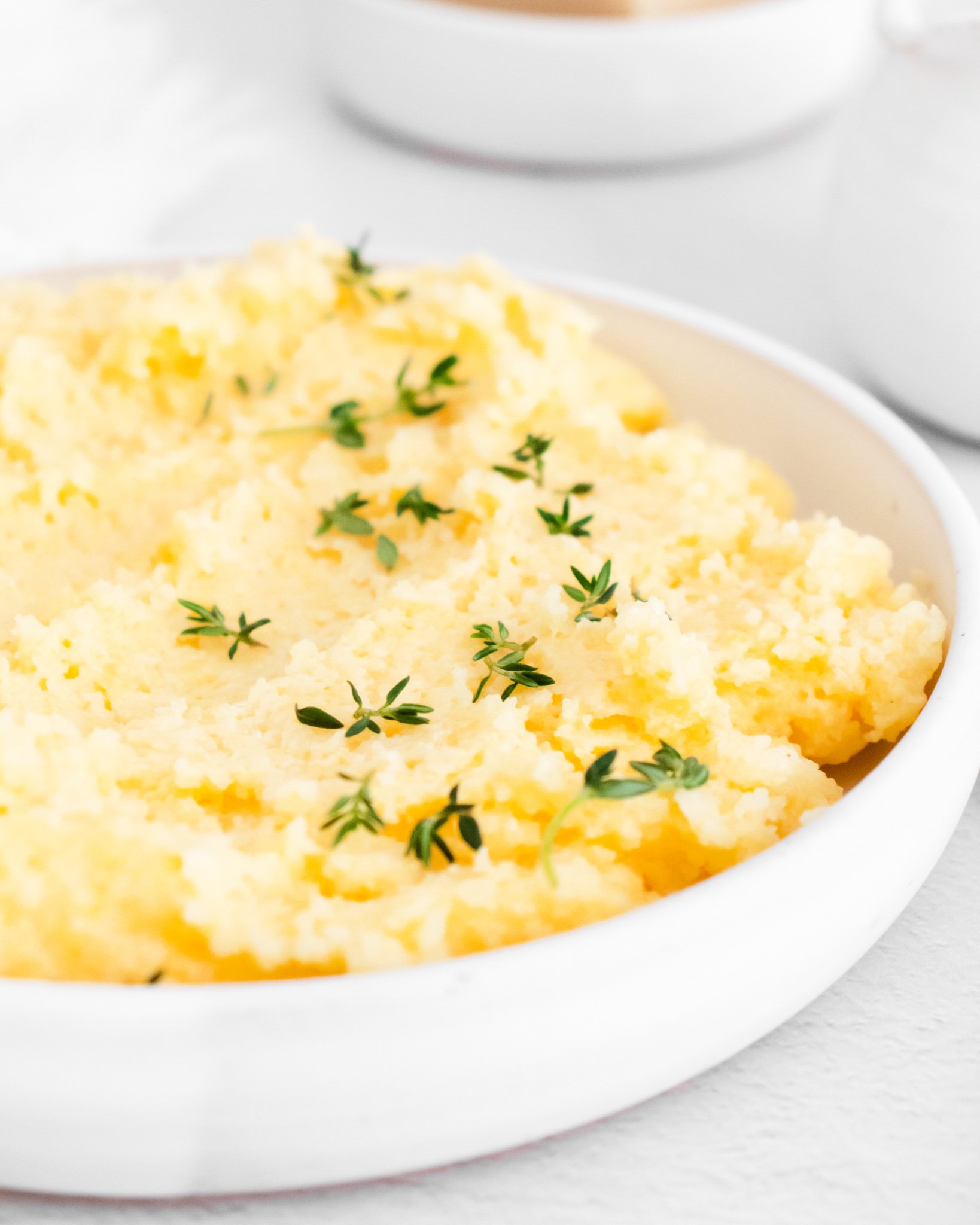Creamy Polenta Recipe with fresh thyme in a bowl.