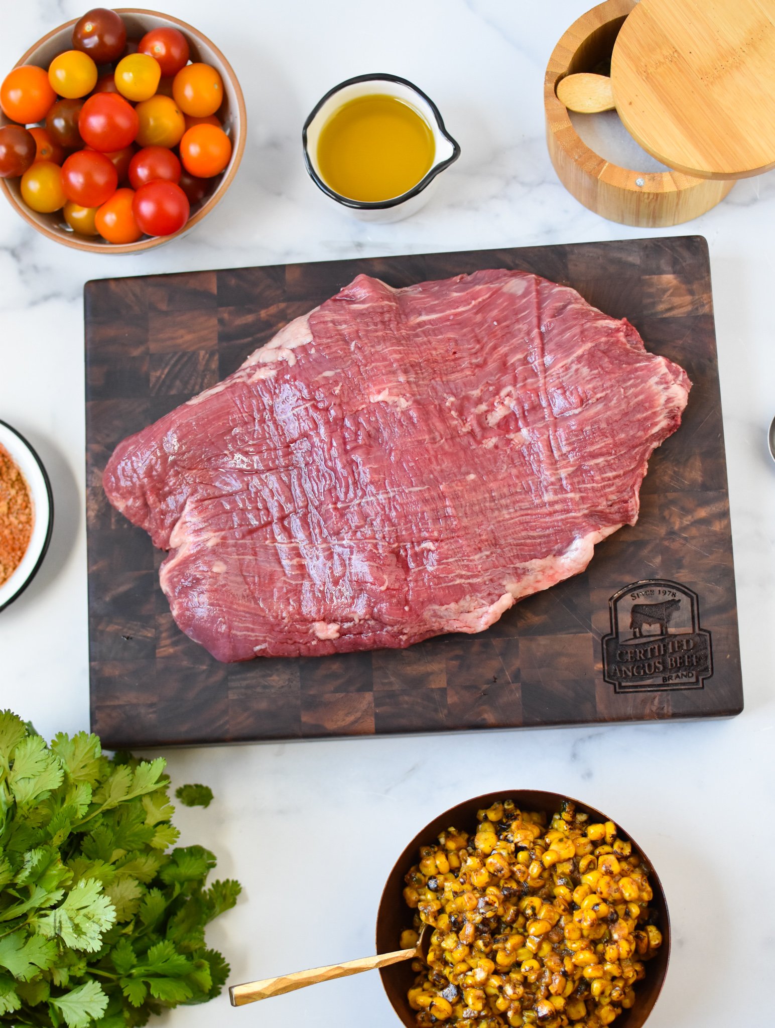 Grilled Flank Steak with Dry Rub ingredients with flank steak on cutting board. 