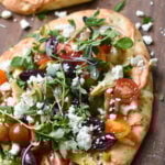 Mediterranean Naan Bread Pizza on a cutting board.