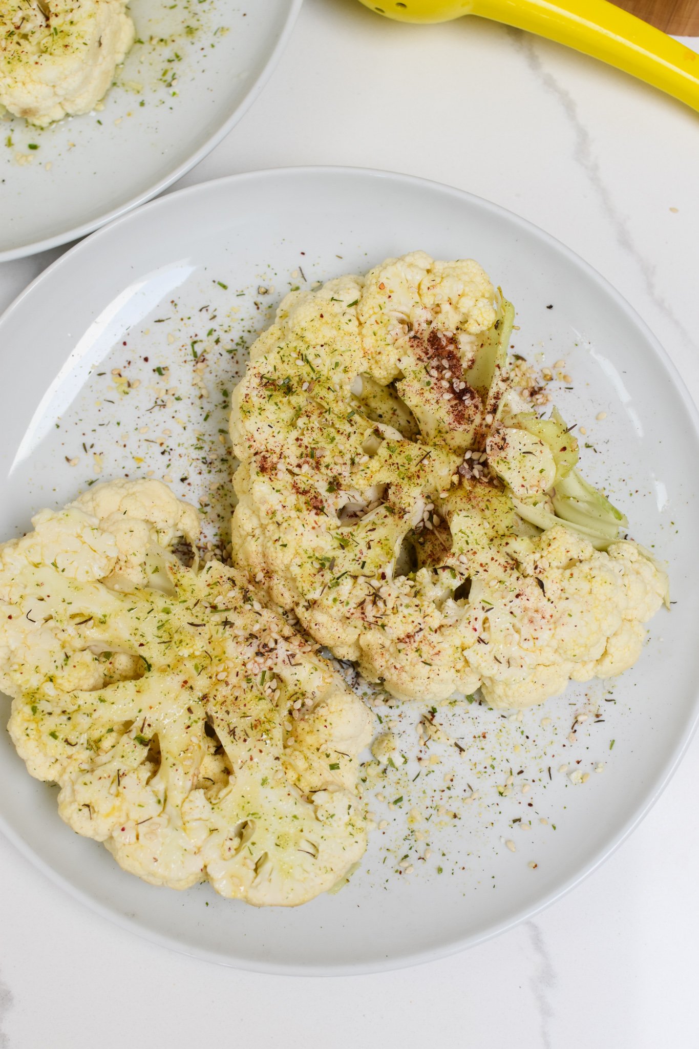 Grilled Cauliflower Steaks with Yogurt Tahini Sauce on a white plate. 