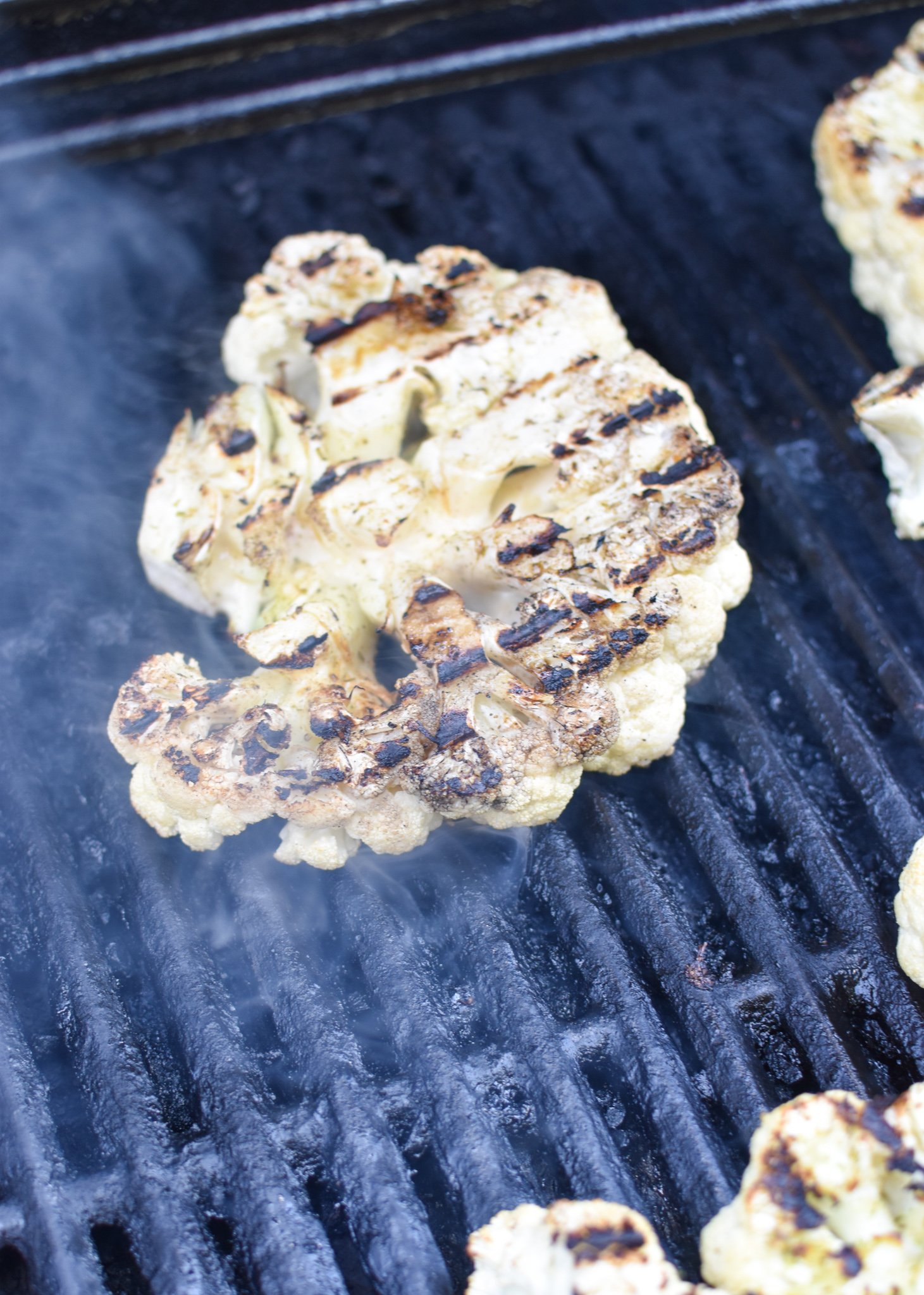 Grilled Cauliflower Steaks with Yogurt Tahini Sauce on grill.