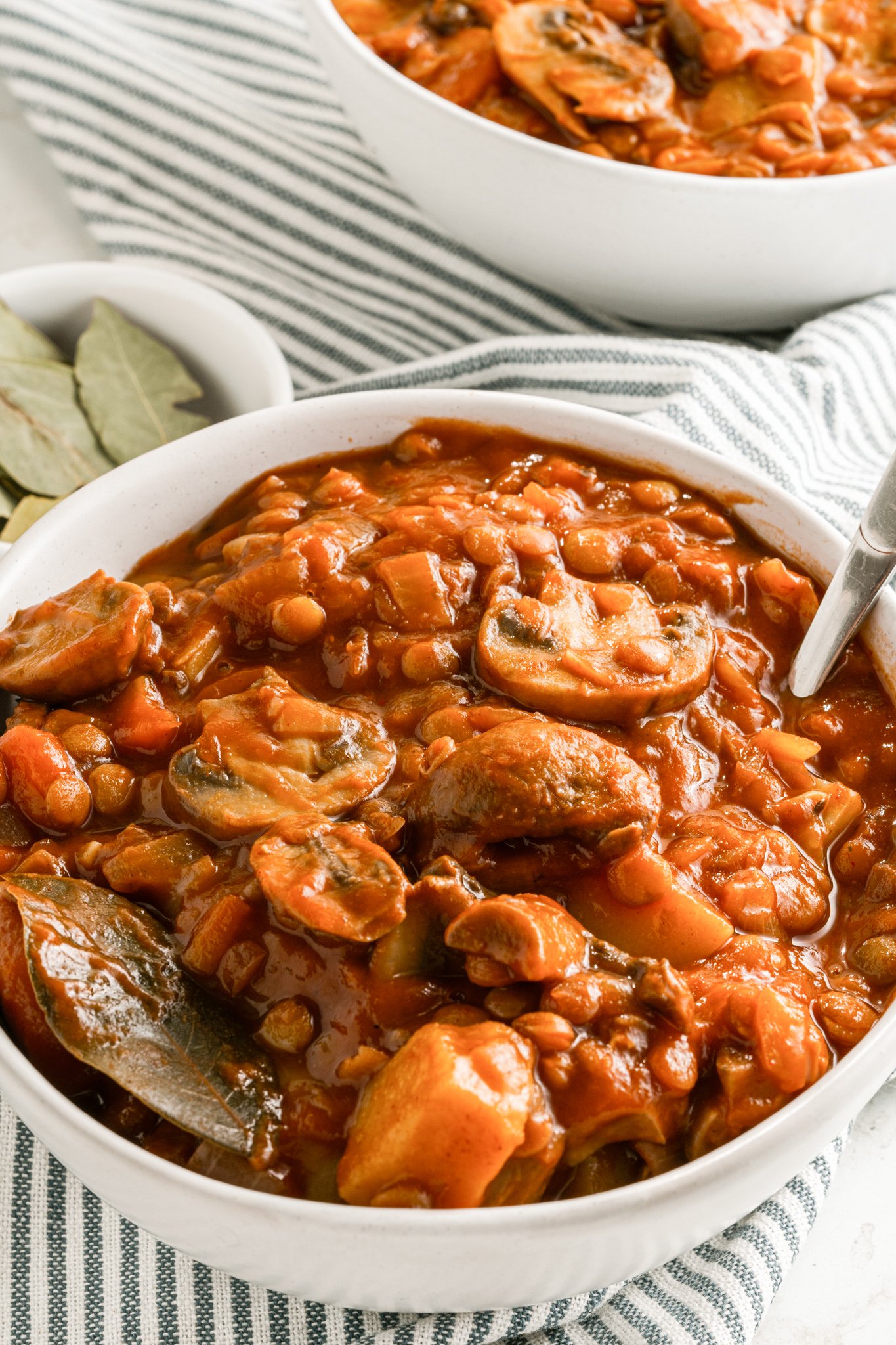 Lentil Mushroom Stew in white bowl with spoon. 
