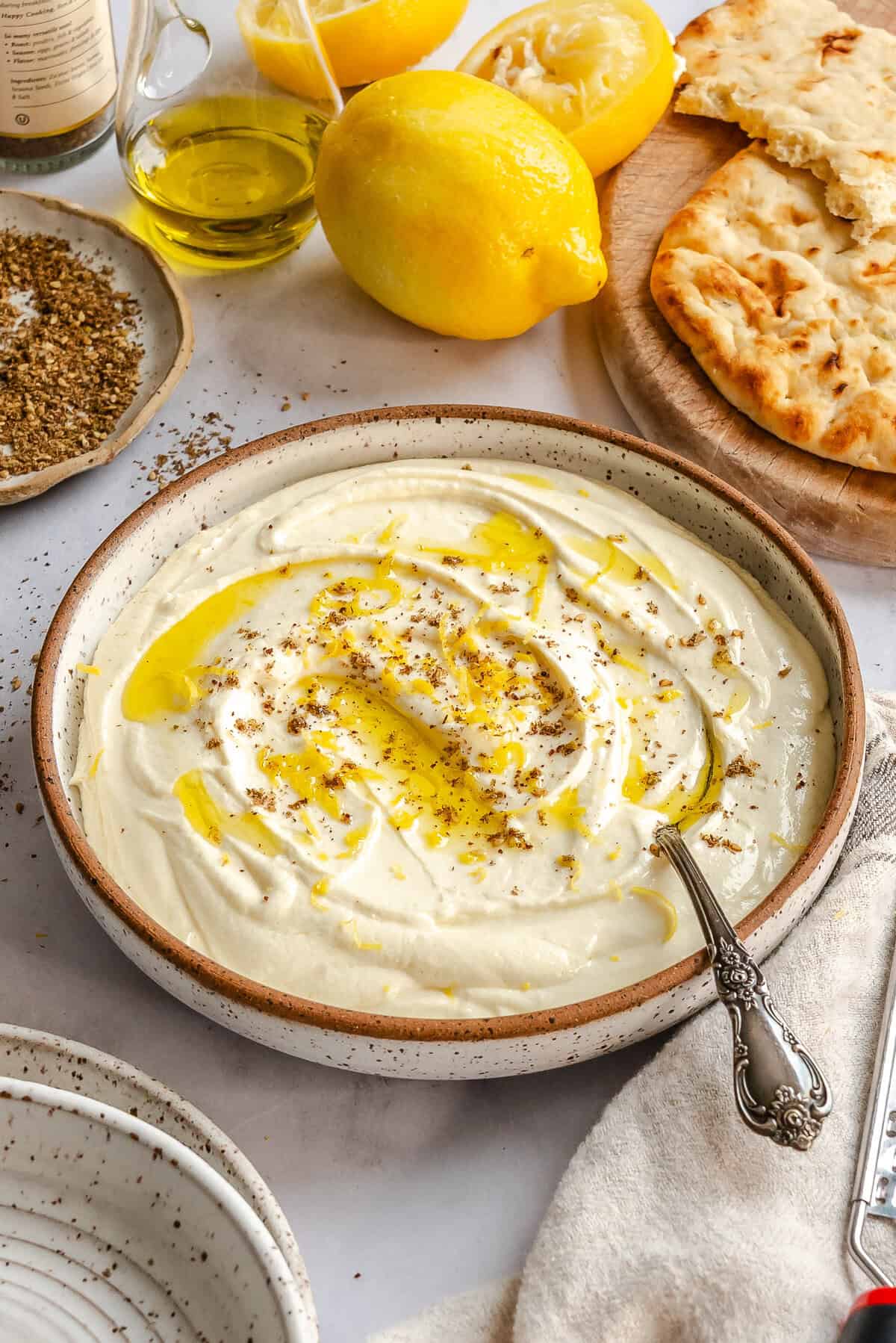 Lemon whipped feta dip served in a white bowl with pita chips on the side