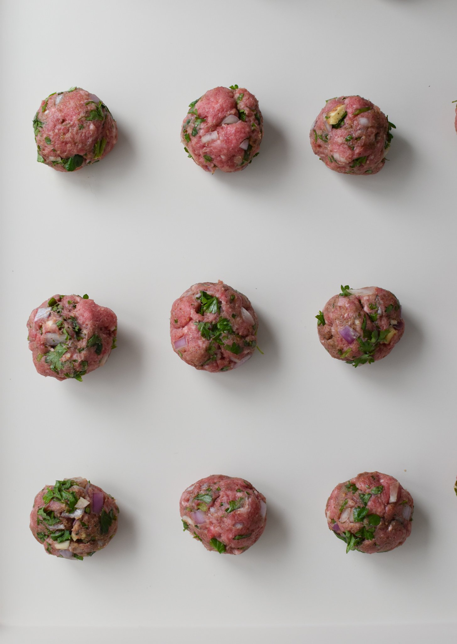 Mediterranean Baked Beef Meatballs meatballs on a baking sheet. 