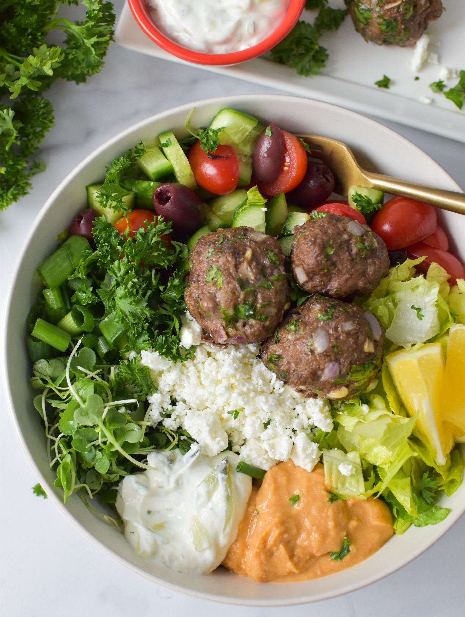 Mediterranean Baked Beef Meatballs in a hummus bowl with vegetables. 