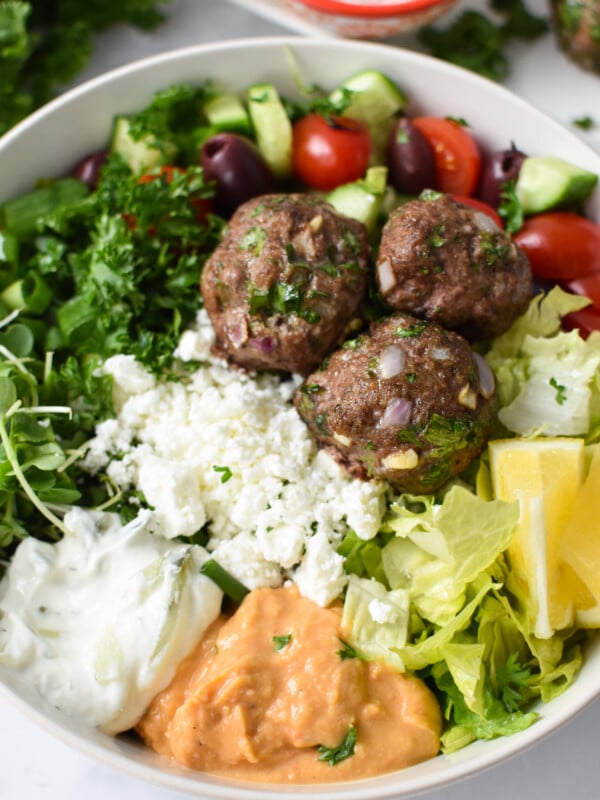 Mediterranean Baked Beef Meatballs in a hummus bowl.