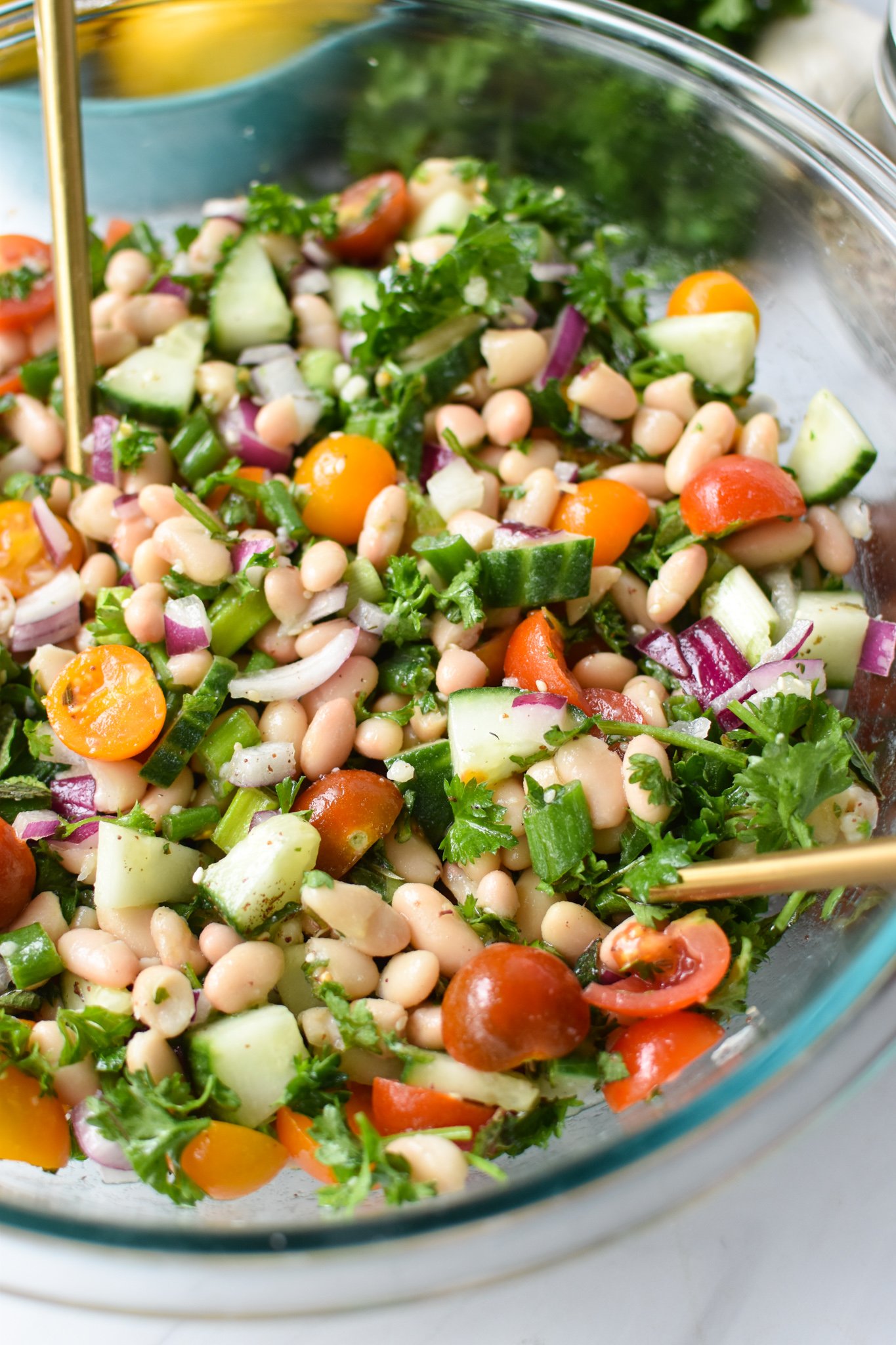 Mediterranean White Bean Salad with gold spoons.