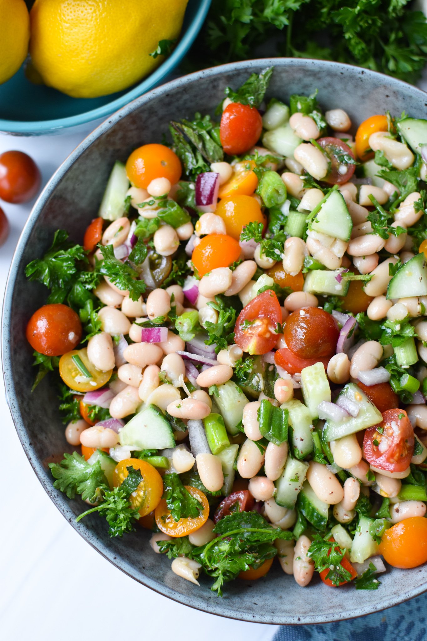 Mediterranean White Bean Salad with parsley and green onions in a blue bowl. 