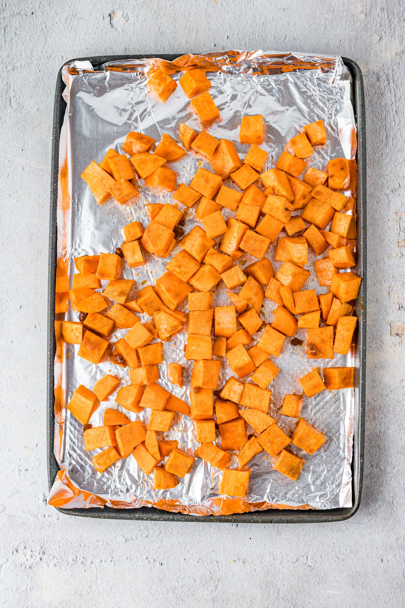 Maple Bourbon Pork Chops Recipe sweet potatoes on a baking sheet. 