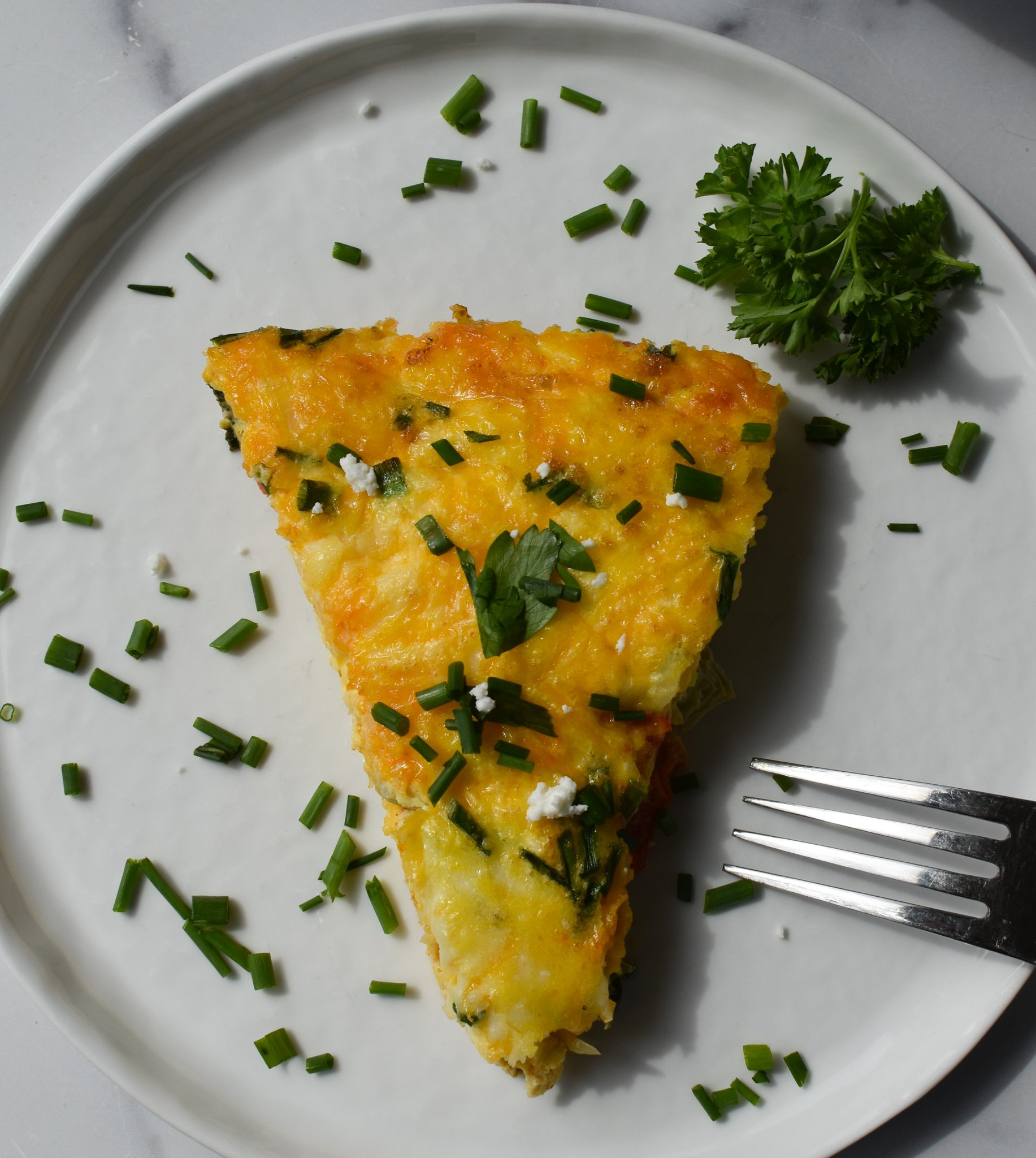 Mediterranean Vegetable Frittata Recipe with a fork on a white plate.